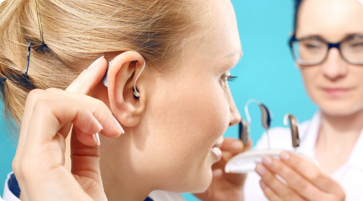 blonde vrouw met achter-het-oor gehoorapparaat voor lichtblauwe achtergrond