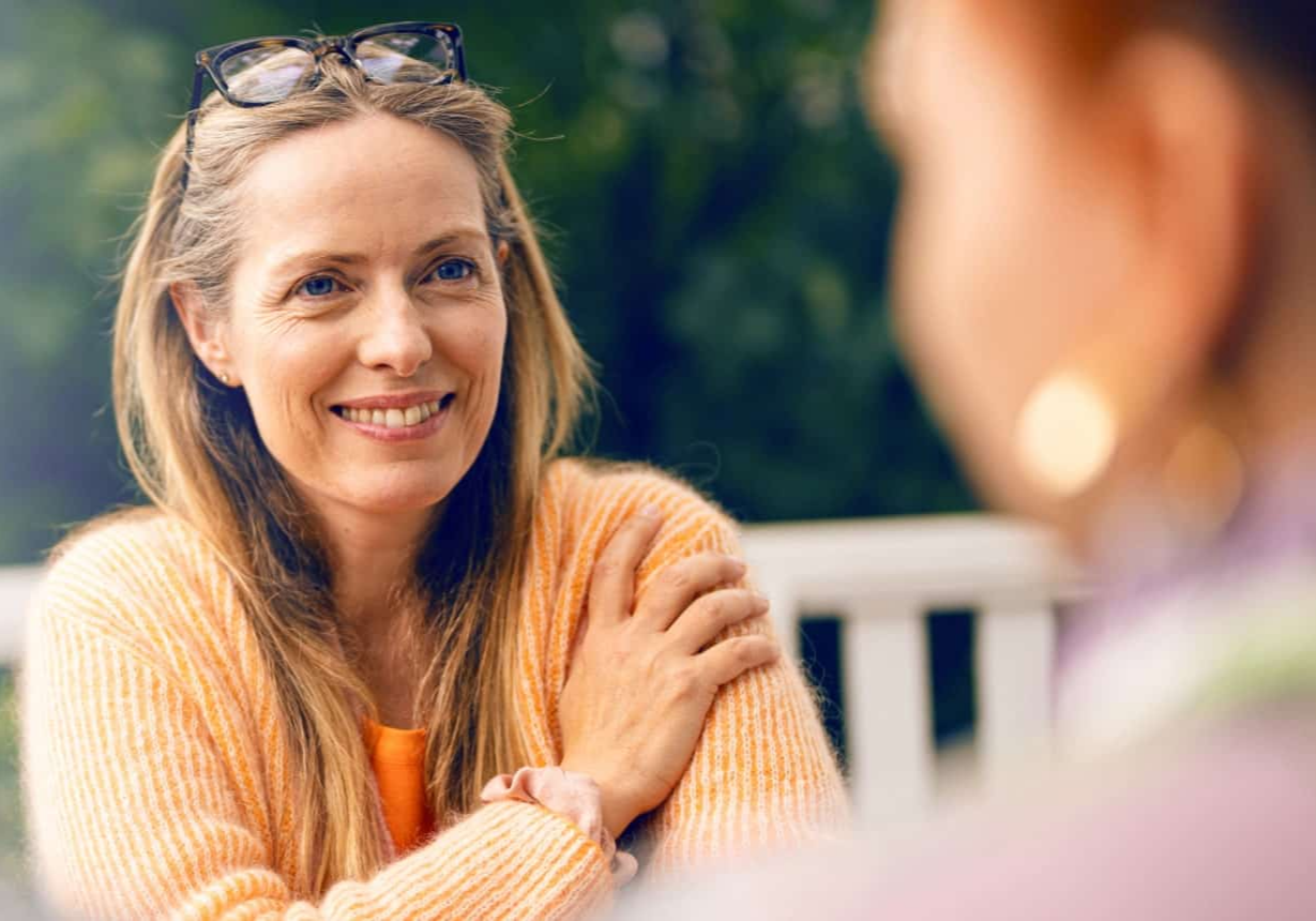 Lachende vrouw in tuin die gezellig een gesprek aan het voeren is