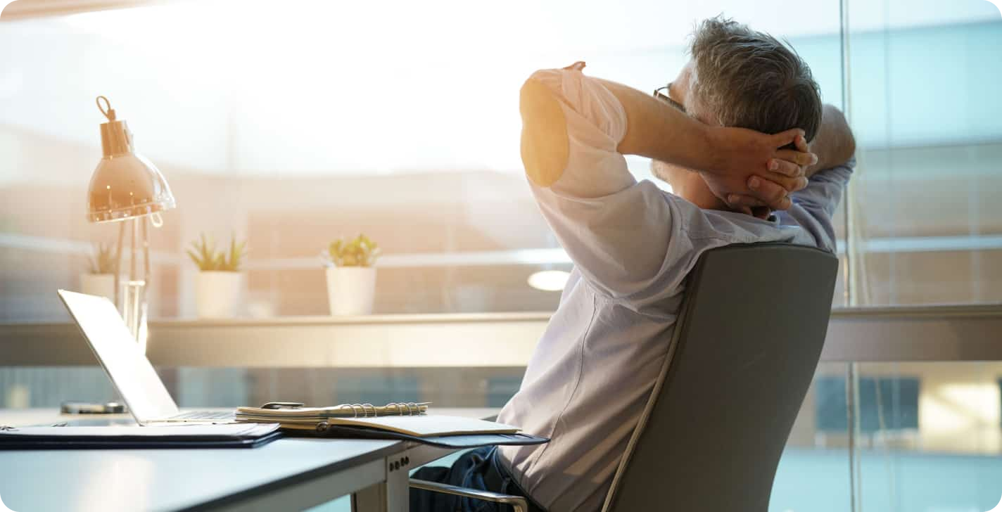 man zit op kantoor met zijn handen achter zijn hoofd