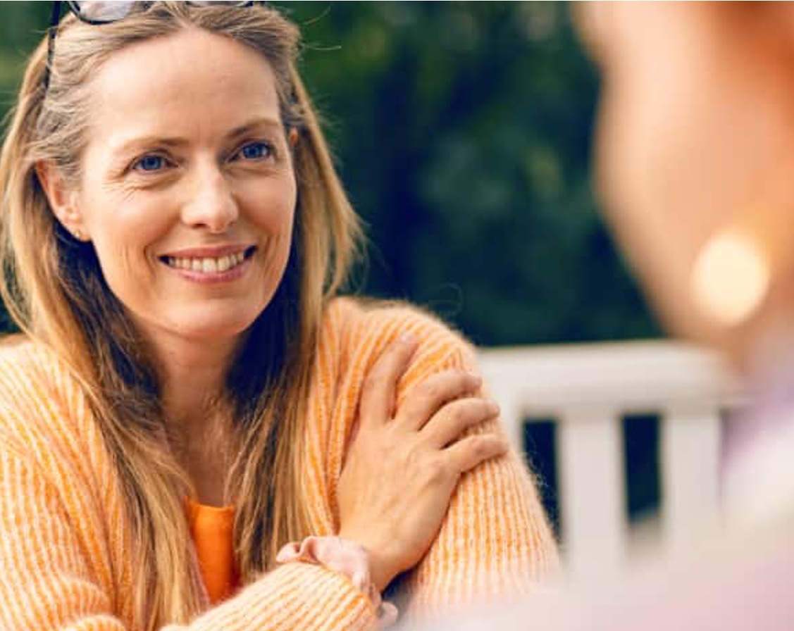 Lachende vrouw in tuin die gezellig een gesprek aan het voeren is