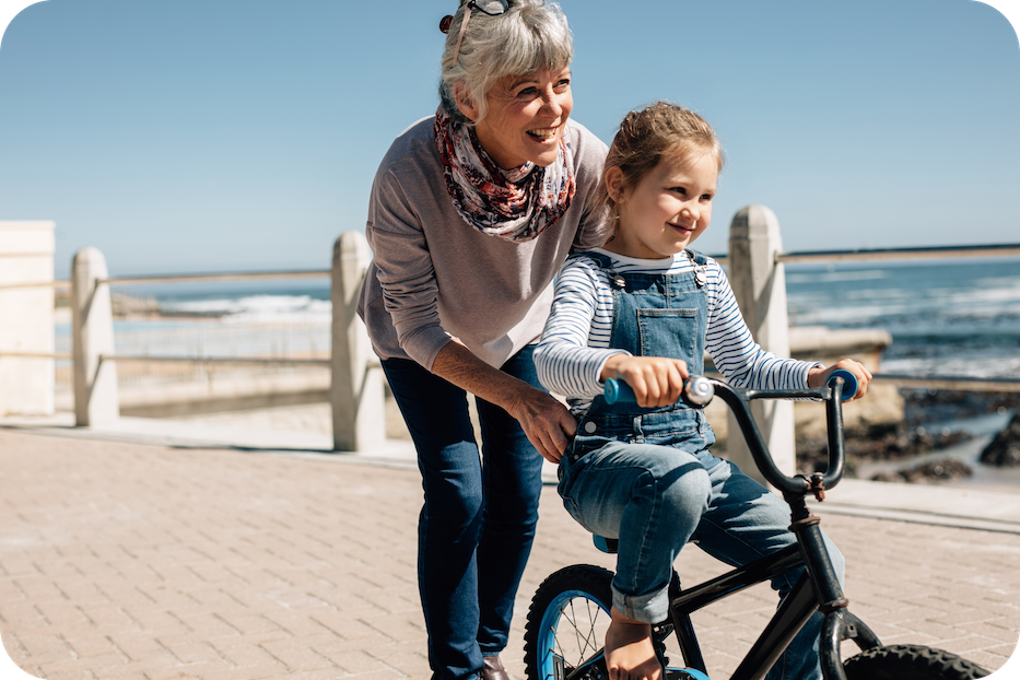 Oma en kleindochter die samen leren fietsen bij de zee 1