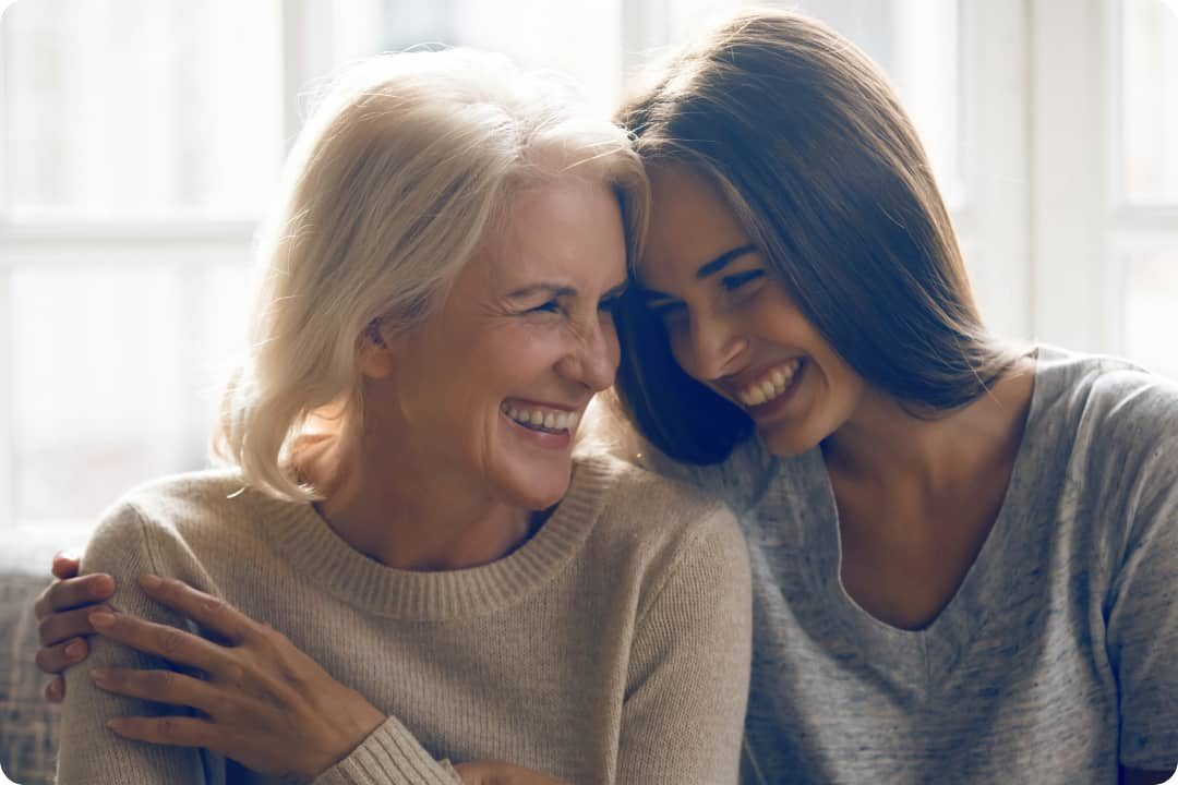 twee vrouwen zitten op de bank en lachen met elkaar