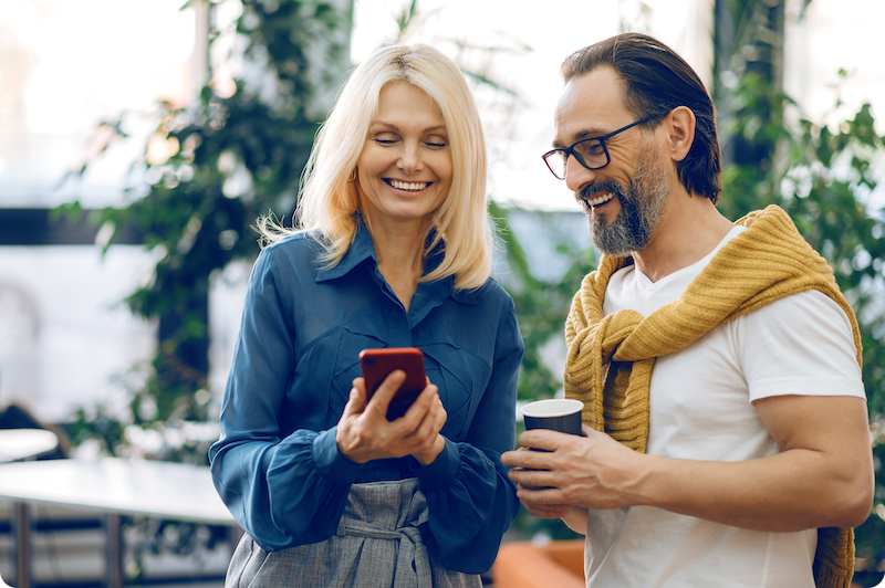 Man en vrouw die een koffie pauze hebben waarbij de vrouw op een telefoon zit