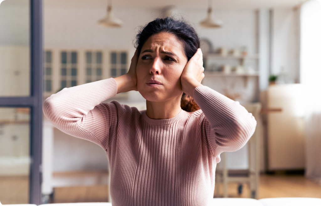 mevrouw heeft haar handen over haar oren terwijl ze moeilijk kijkt